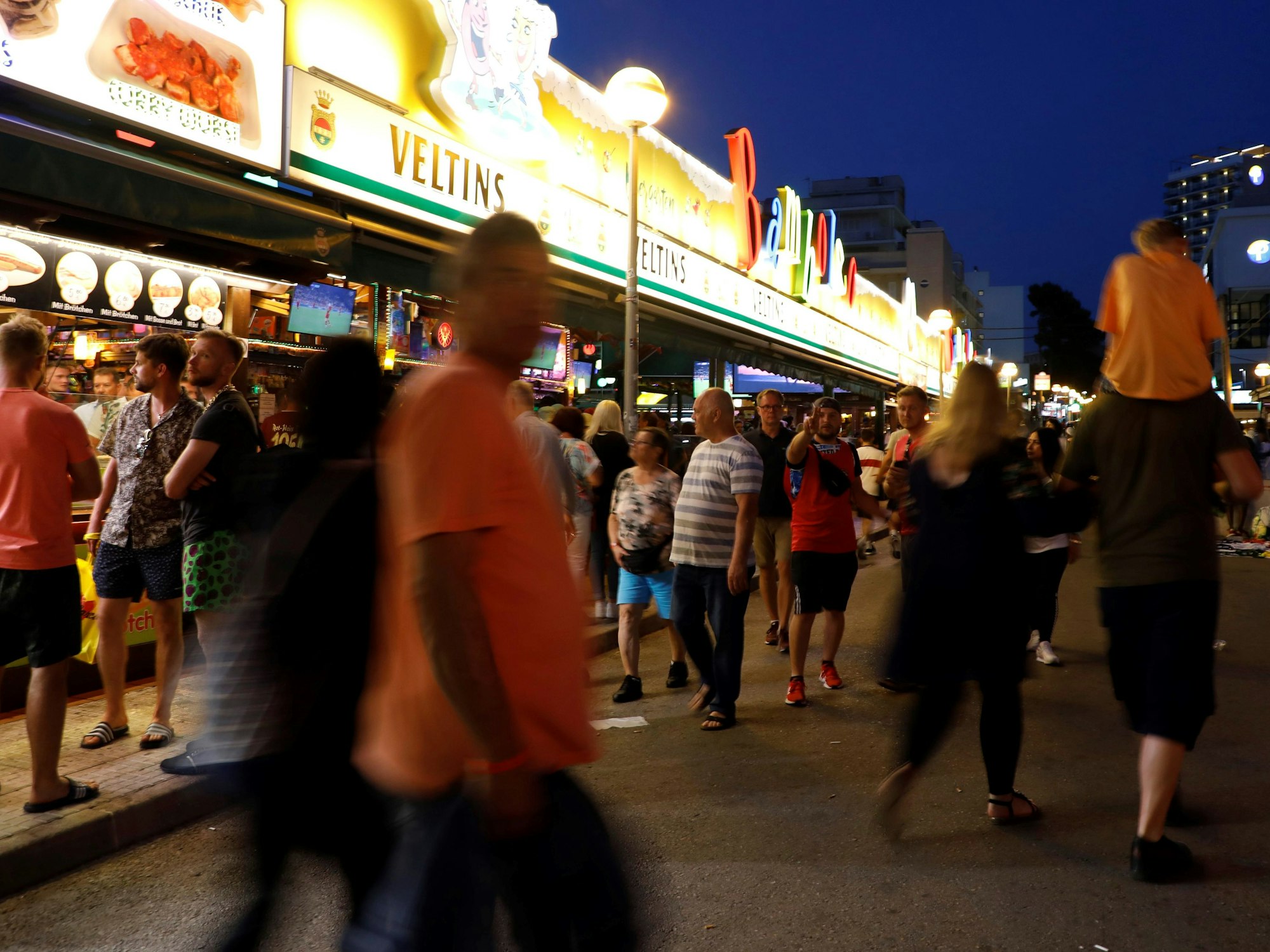 Menschen gehen an der Bar Bamboleo in der Bierstraße am Ballermann vorbei.