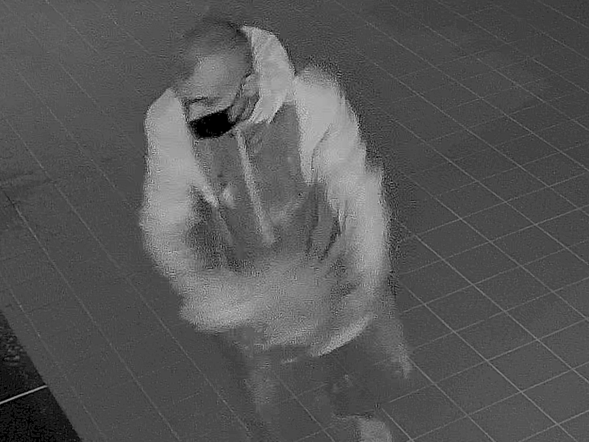 Mann steht in dunkler Pizzeria und verschüttet eine Flüssigkeit.