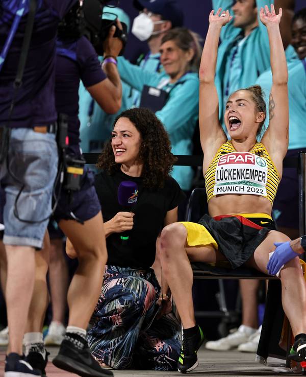 Gina Lückenkemper macht mit den Fans La-Ola. Sanitäter versorgen dabei ihre Wunde.