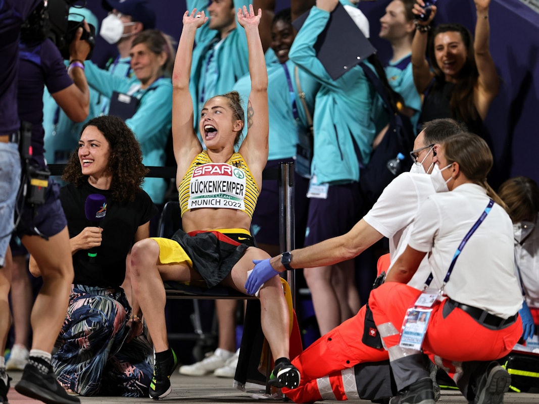 Gina Lückenkemper macht mit den Fans La-Ola. Sanitäter versorgen dabei ihre Wunde.