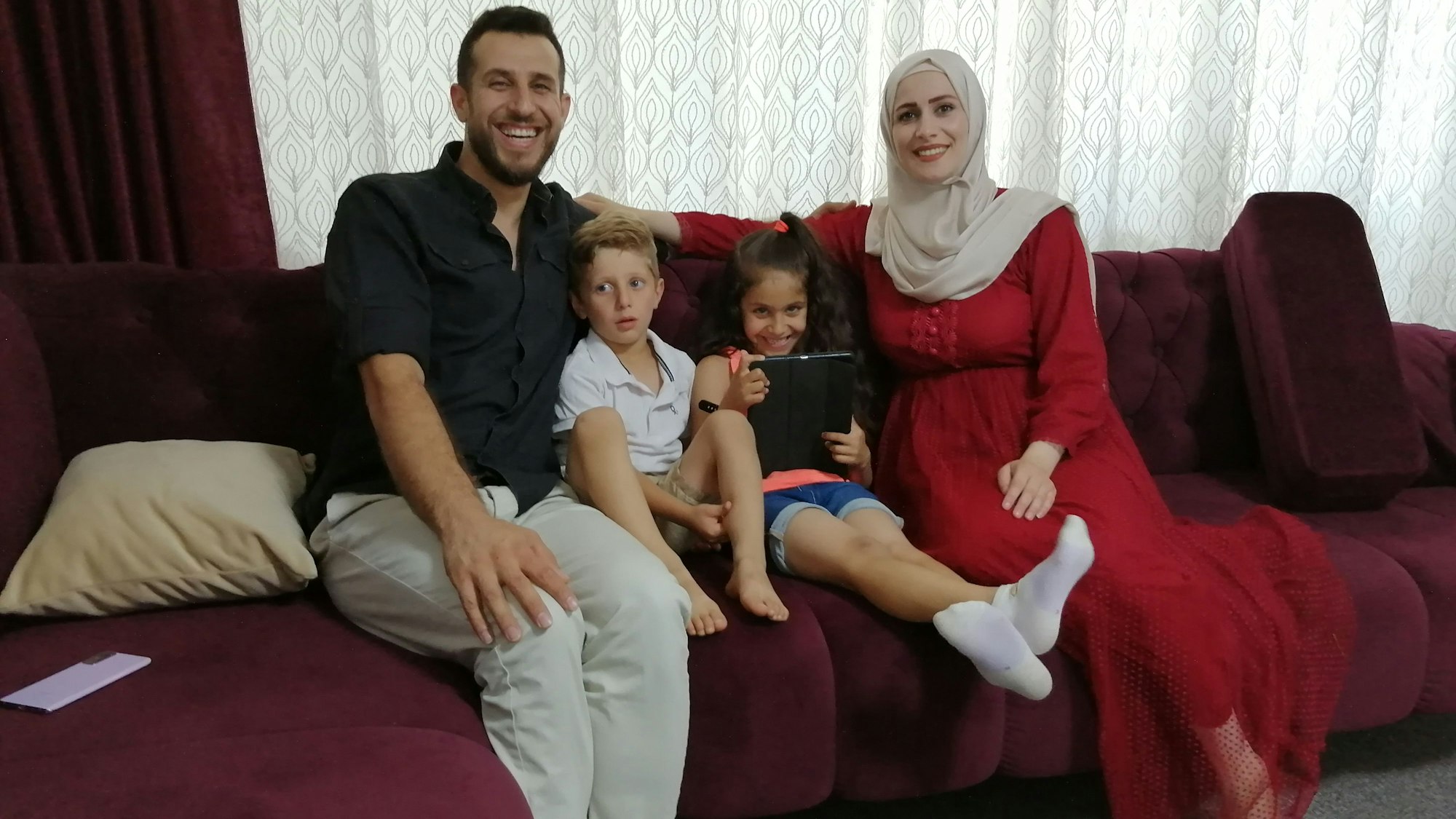 Die Kölnerin Angela mit ihrer Familie auf dem Sofa in ihrer Wohnung.