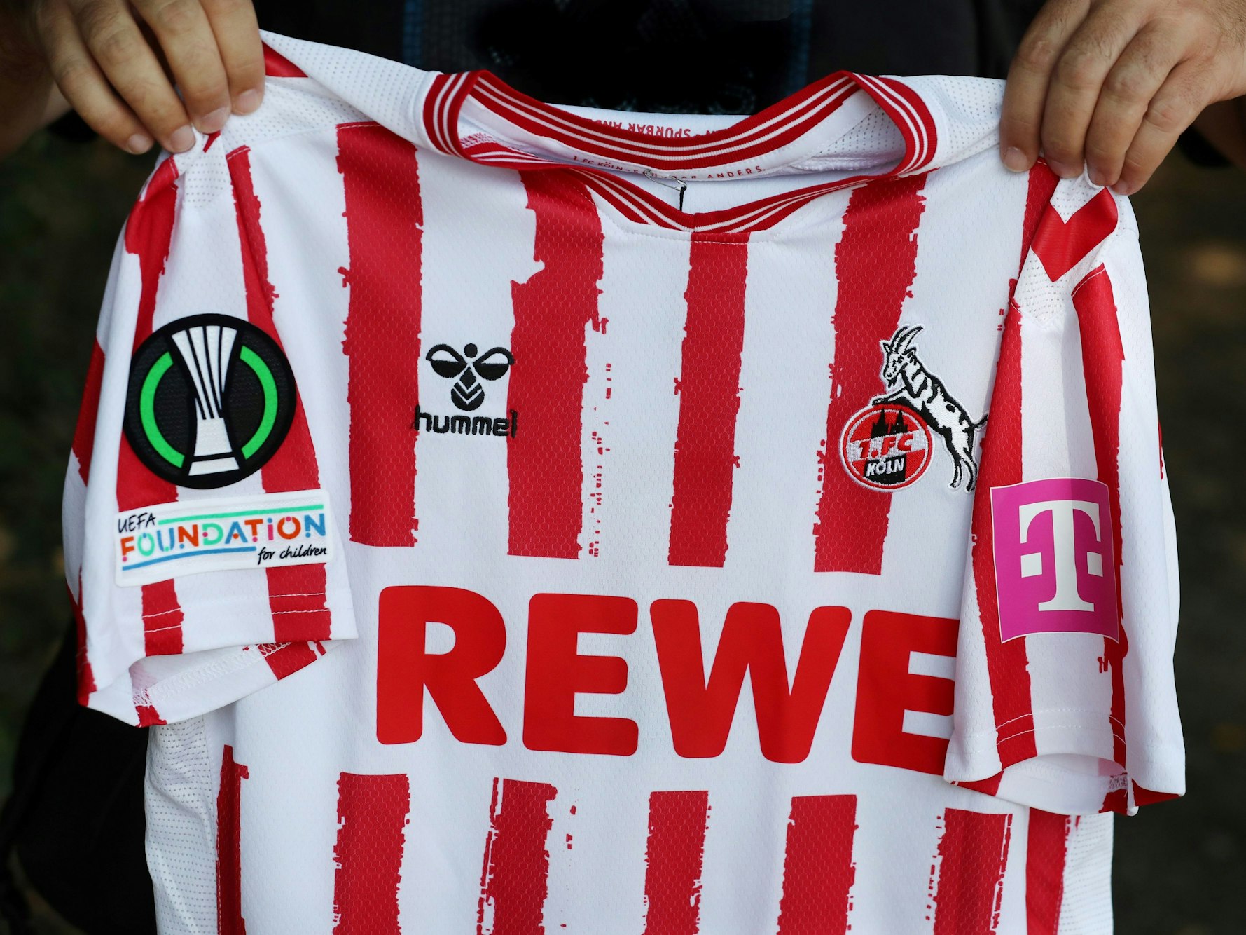 Ein Mann hält ein Fußballtrikot in den Händen.