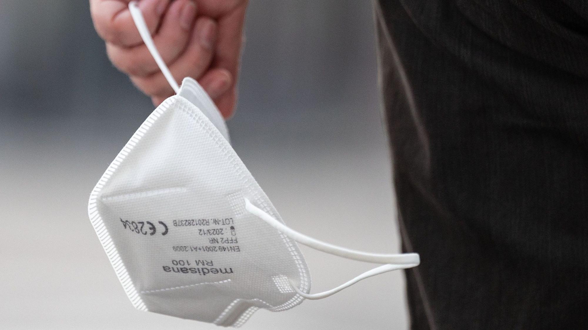 Eine Passantin trägt am 3. August 2022 eine FFP2-Maske in der Hand. NRW hat die bisherigen Corona-Schutzmaßnahmen vorzeitig bis weit in den September hinein verlängert.
