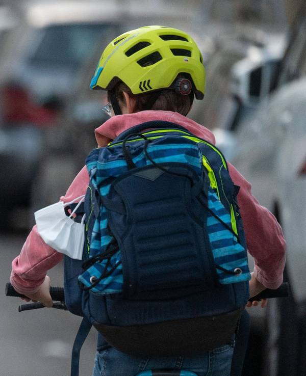 Ein Schulkind fährt mit seinem Fahrrad eine Straße entlang.