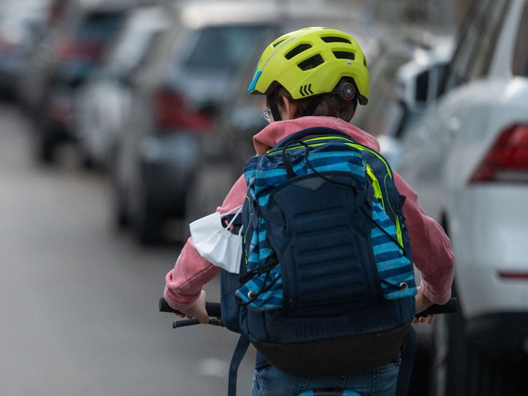 Ein Schulkind fährt mit seinem Fahrrad eine Straße entlang.