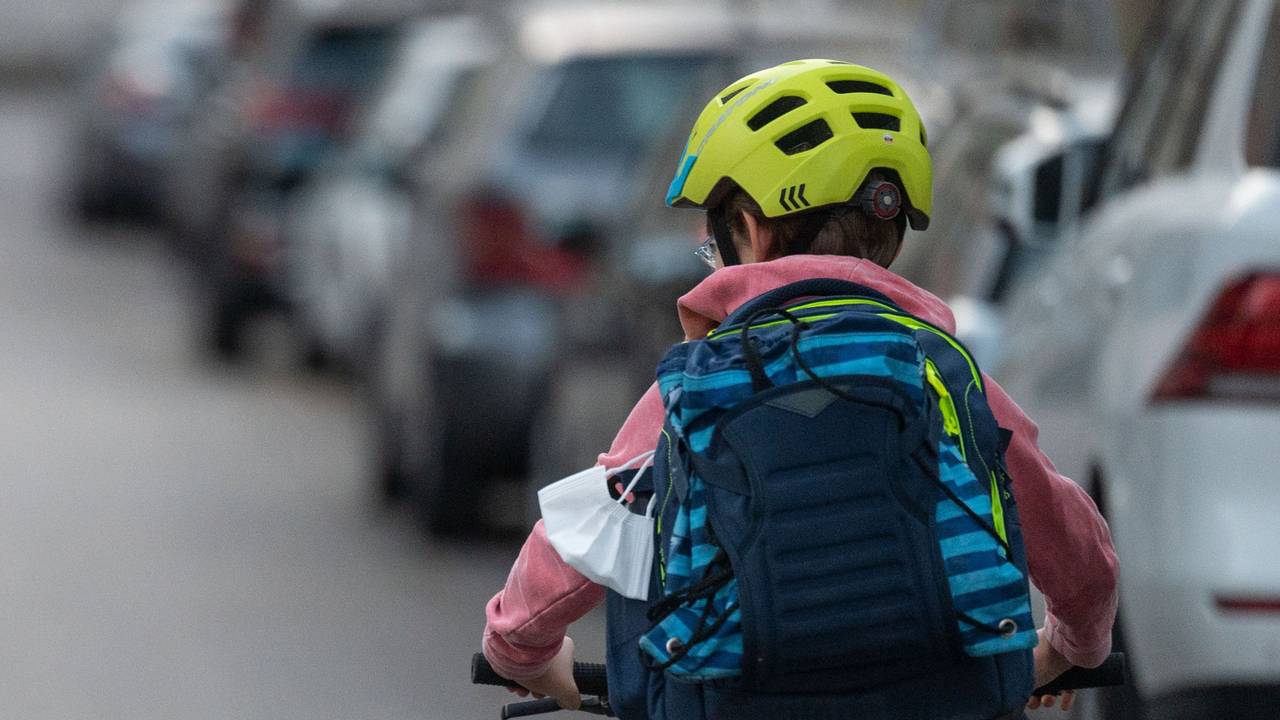 Ein Schulkind fährt mit seinem Fahrrad eine Straße entlang.