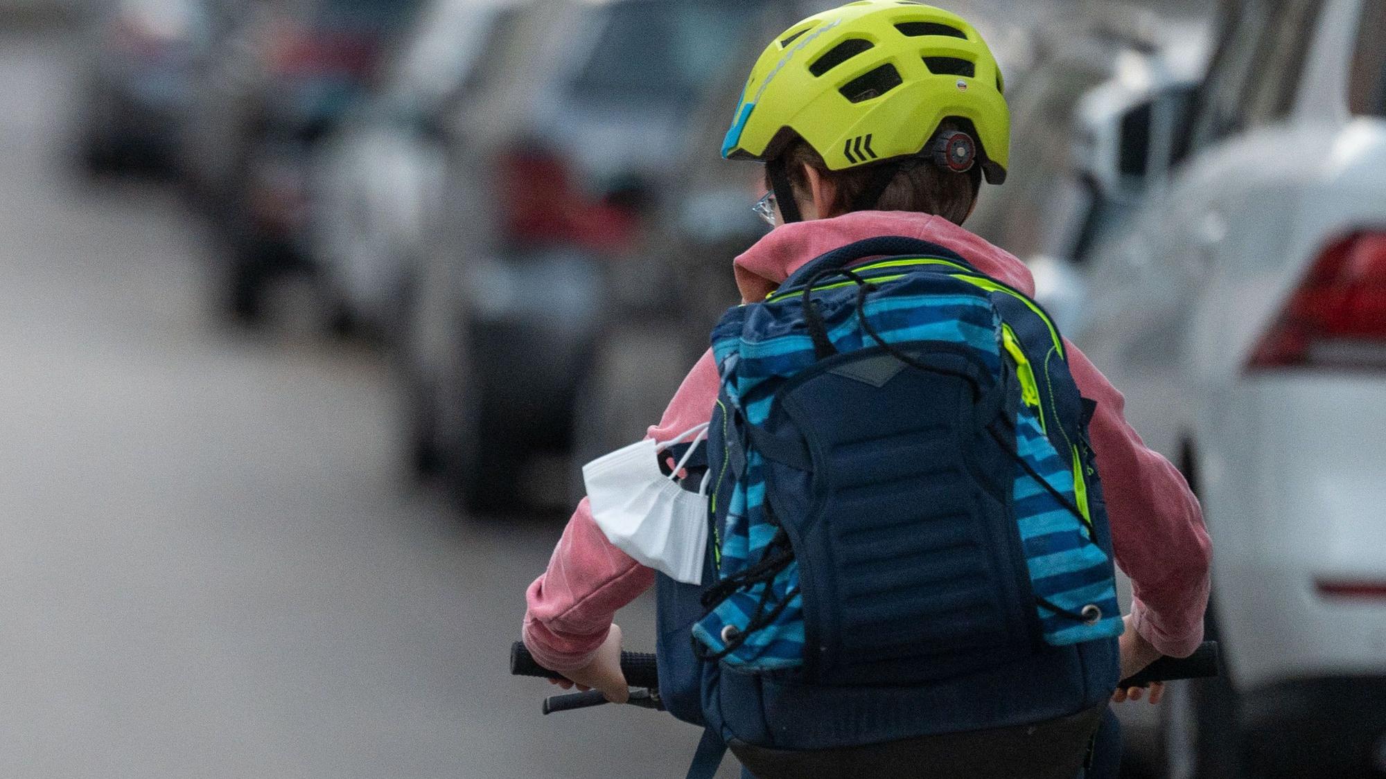Ein Schulkind fährt mit seinem Fahrrad eine Straße entlang.