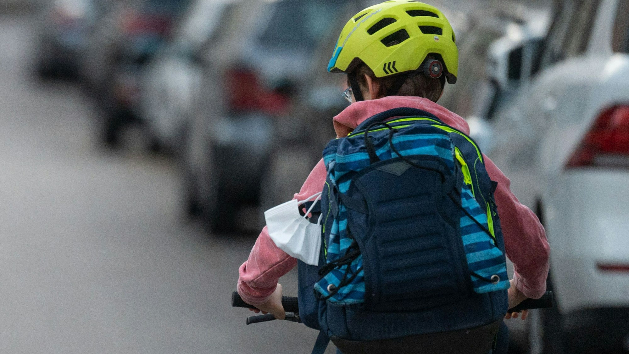 Ein Schulkind fährt mit seinem Fahrrad eine Straße entlang.