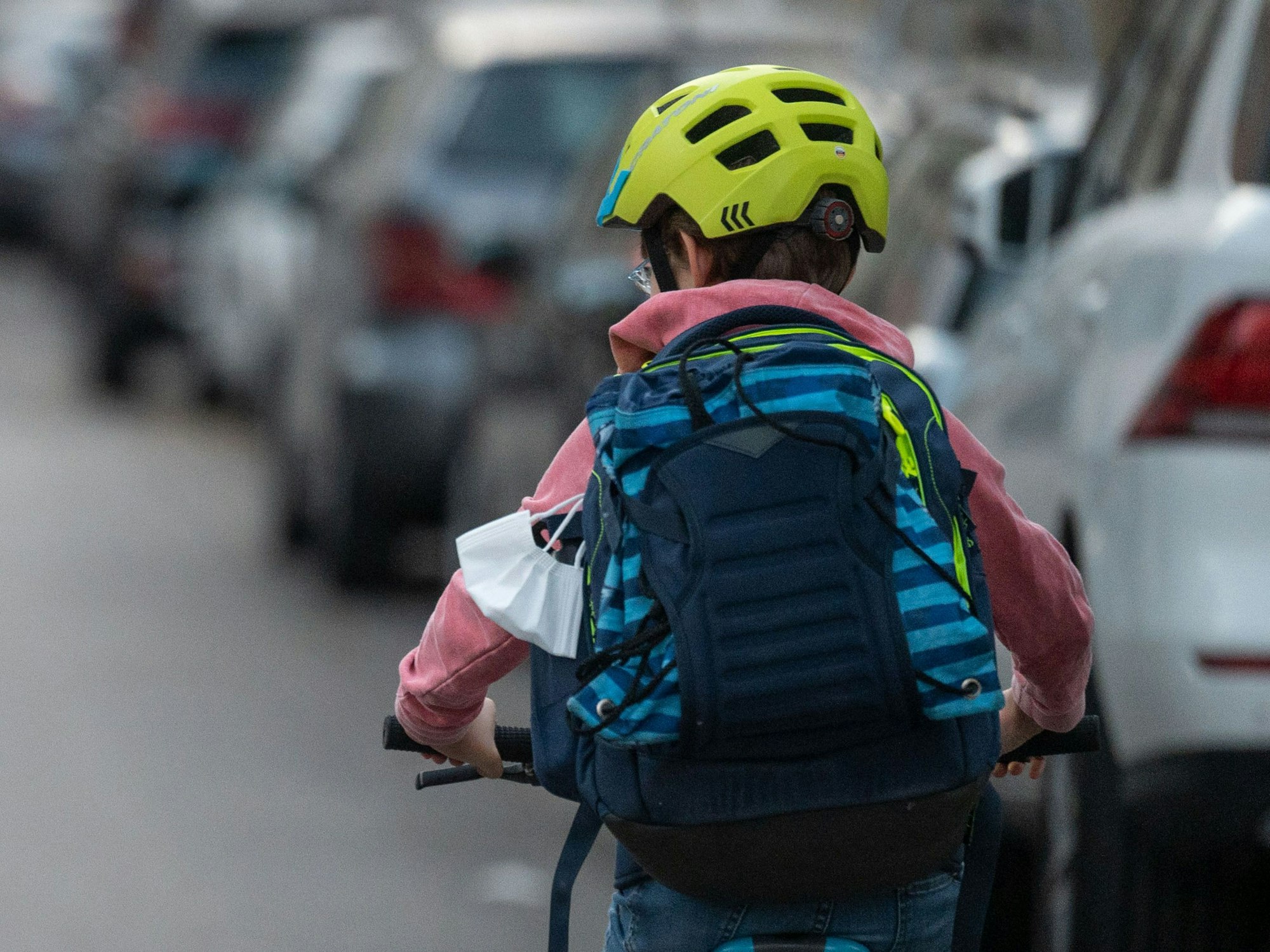 Ein Schulkind fährt mit seinem Fahrrad eine Straße entlang.