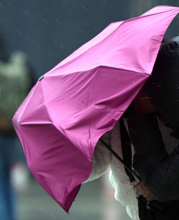 Eine Passantin in Köln kämpft bei Regen und Sturm mit ihrem Regenschirm. Symbolaufnahme von Februar 2022.