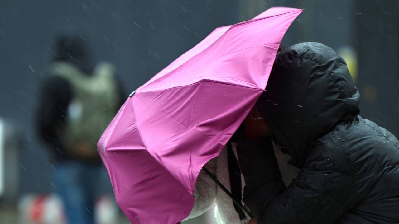 Eine Passantin in Köln kämpft bei Regen und Sturm mit ihrem Regenschirm. Symbolaufnahme von Februar 2022.