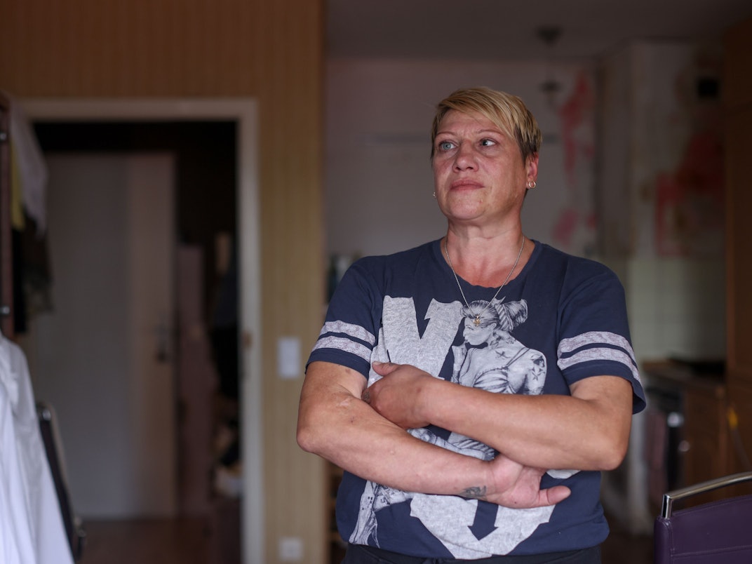 Angela Aranov steht mit verschränkten Armen in ihrer Wohnung.