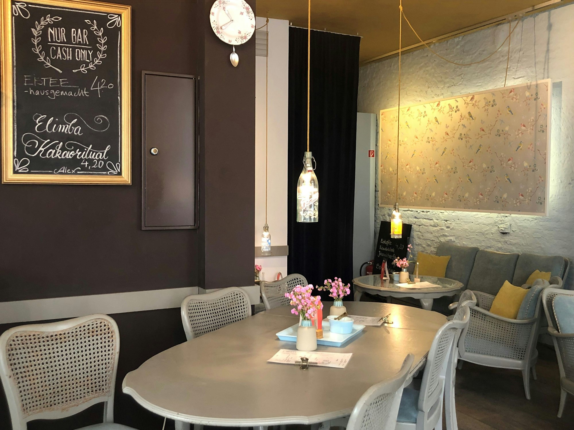 Der Gastraum des Cafés mit einem großen Tisch in der Mitte und einer gemütlichen Sofa-Ecke.
