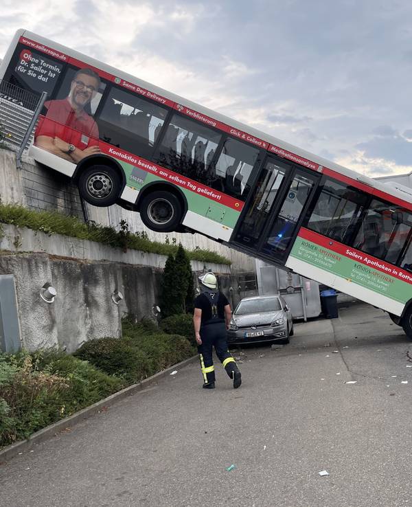 Der hintere Teil eines Busses hängt an einer Mauer, der vordere Teil landete in der Fassade eines Discounters.