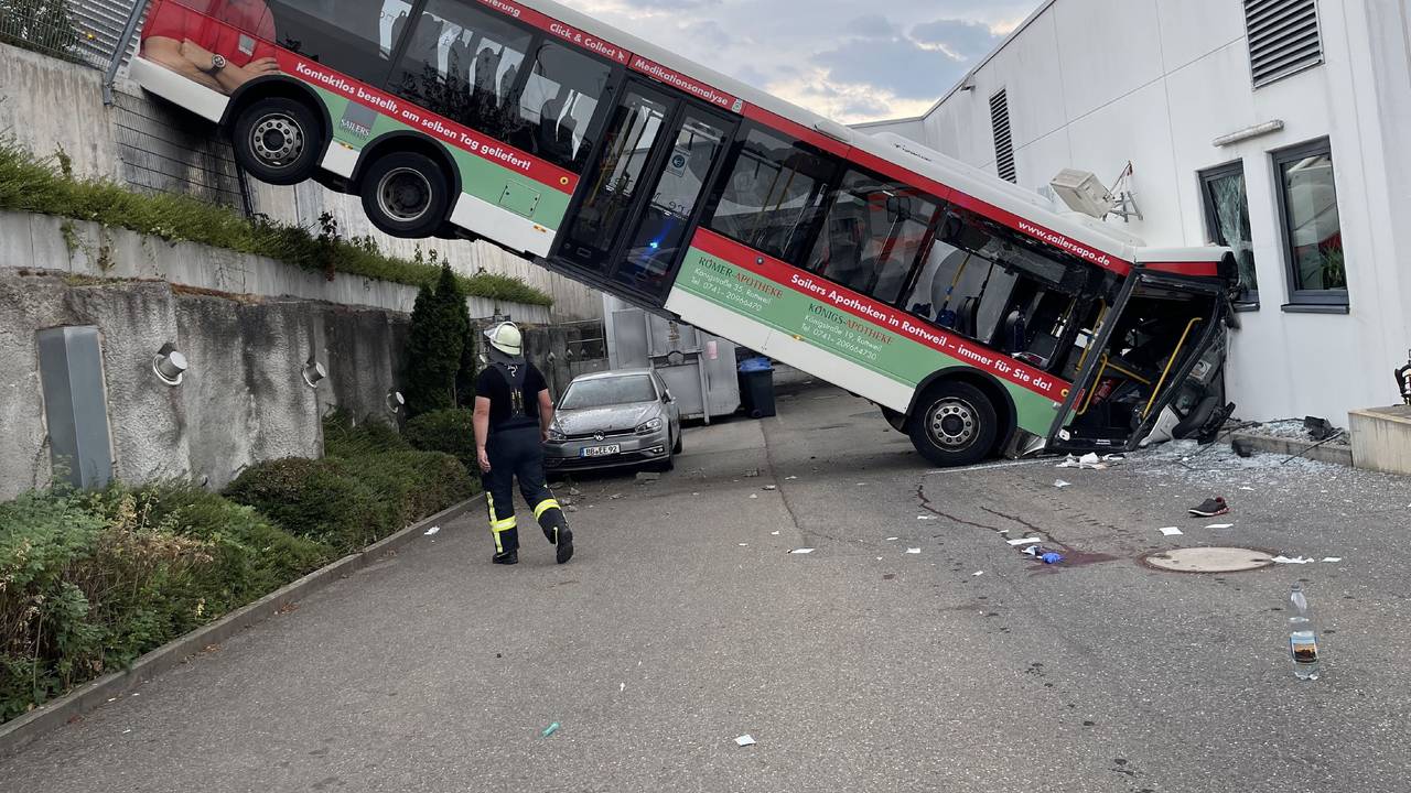 Der hintere Teil eines Busses hängt an einer Mauer, der vordere Teil landete in der Fassade eines Discounters.