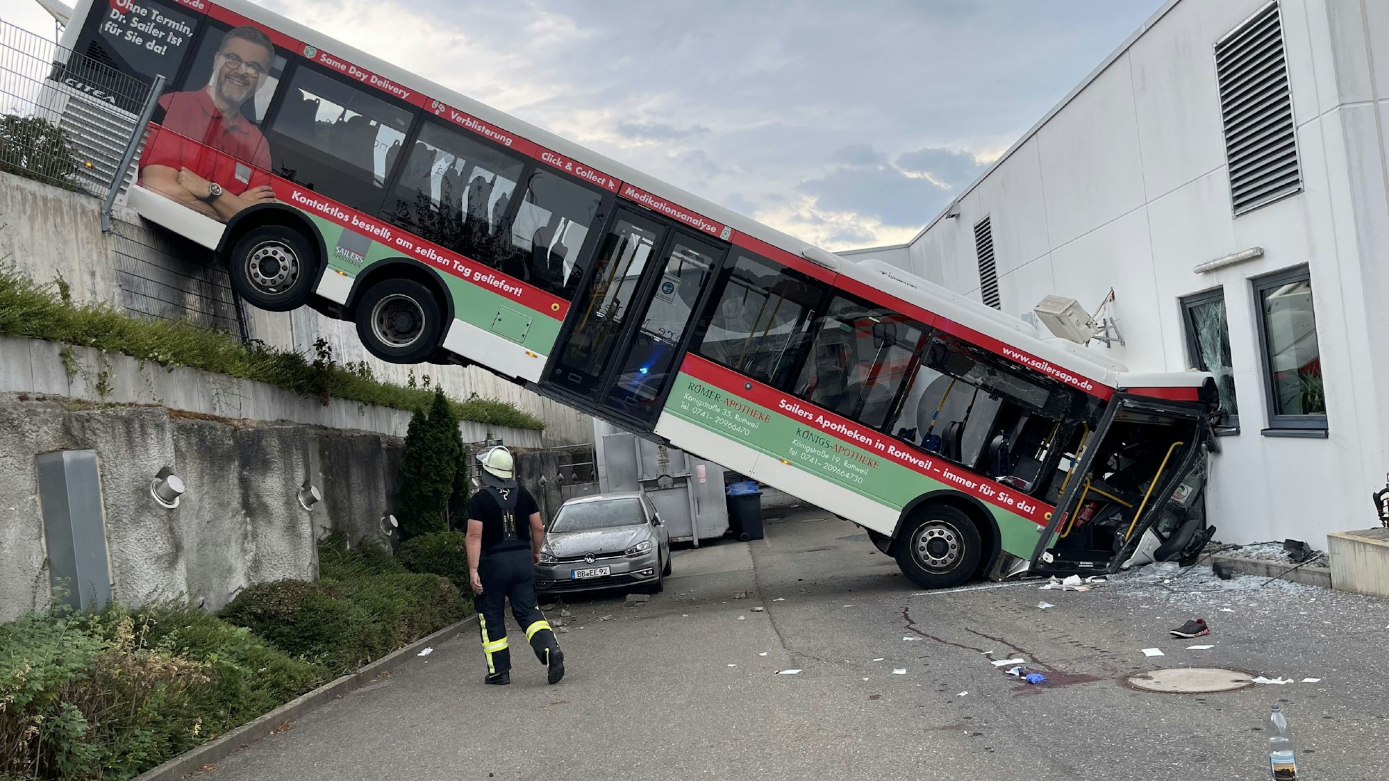 Der hintere Teil eines Busses hängt an einer Mauer, der vordere Teil landete in der Fassade eines Discounters.