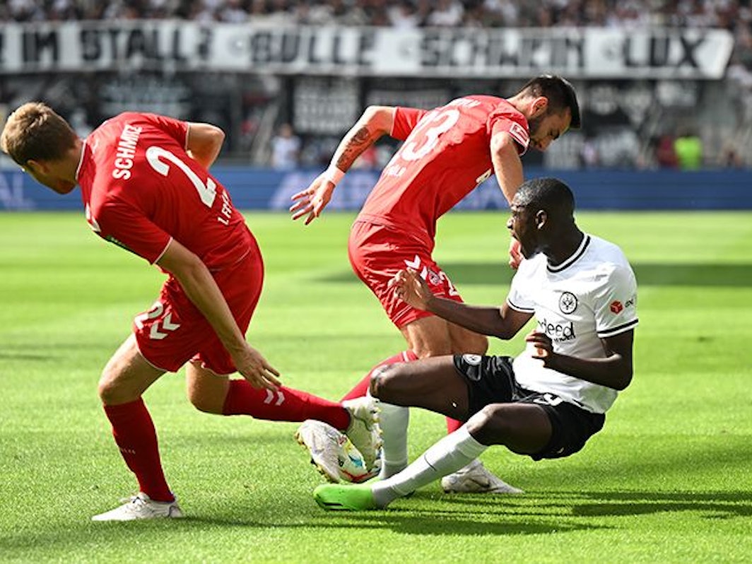 Die Kölner Benno Schmitz und Sargis Adamyan kämpfen mit Frankfurts Randal Kolo Muani um den Ball.
