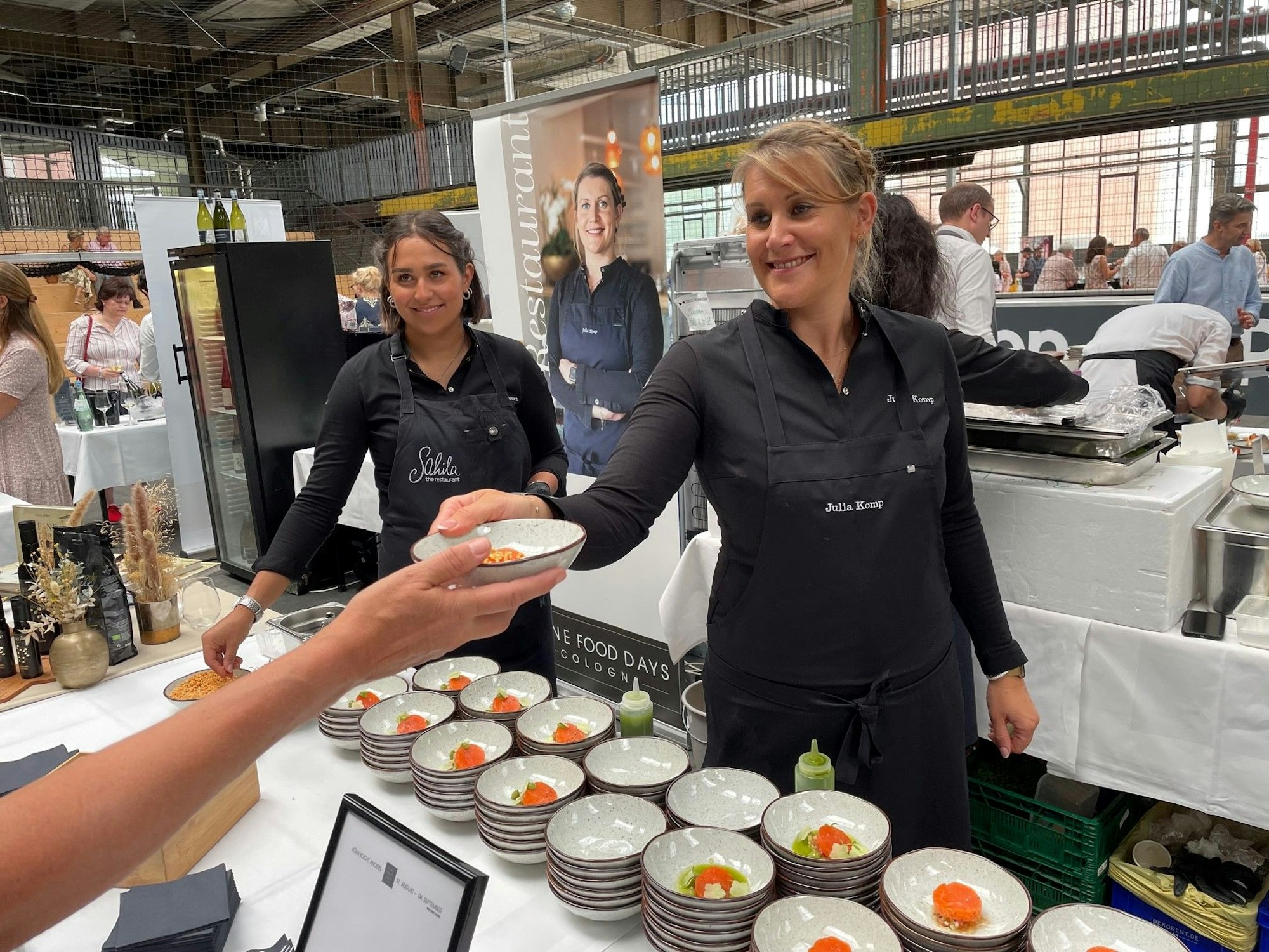 Starköchin Julia Komp reicht einen Teller.