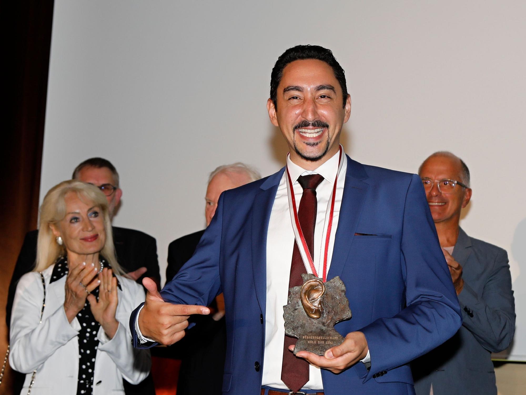 Rapper Eko Fresh hält einen Orden als Auszeichnung in der Hand.