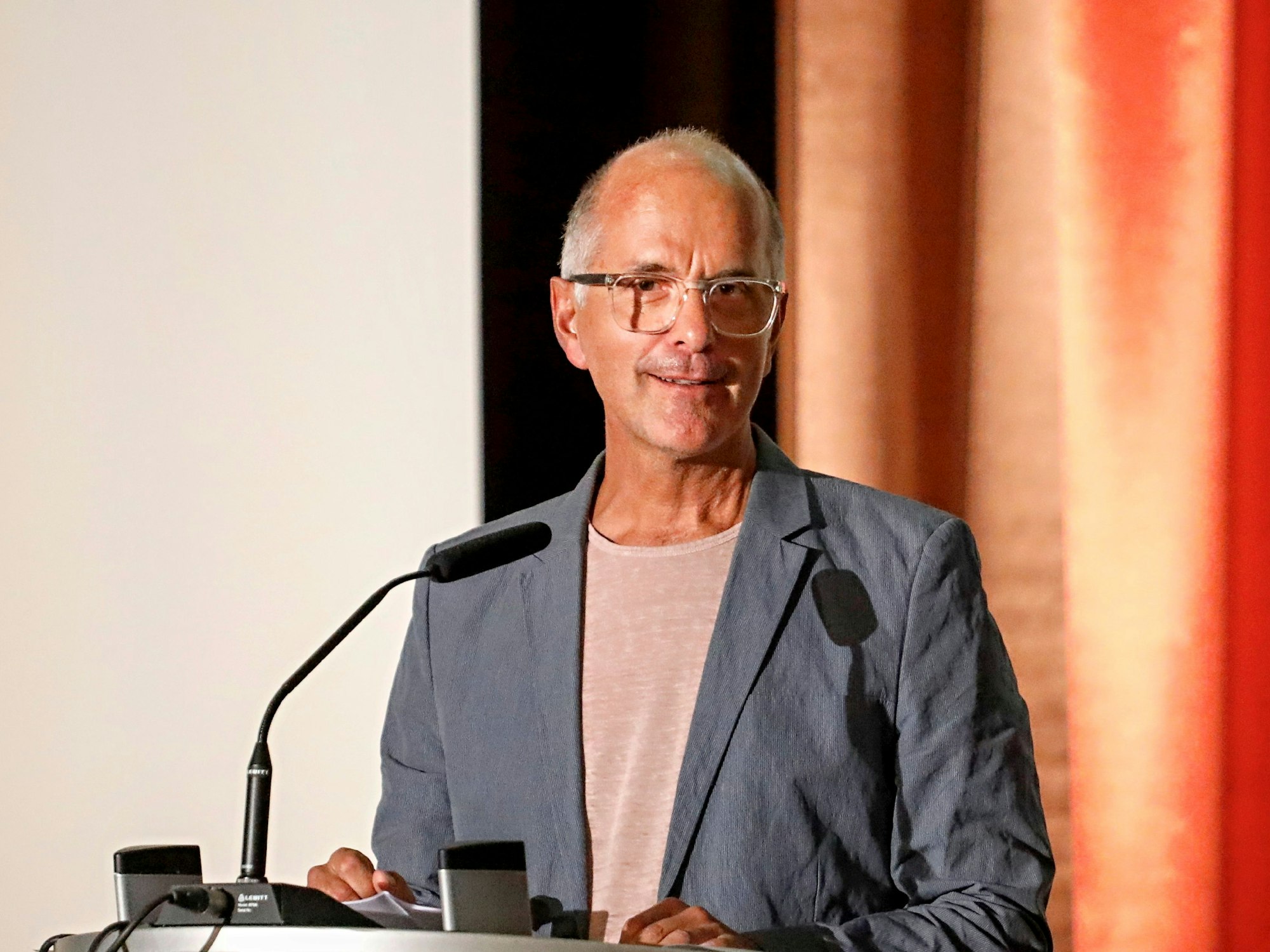 Christoph Maria Herbst steht vor einem Mikrofon.