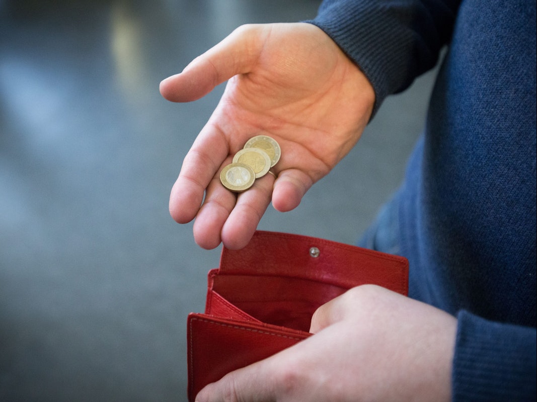 Münzen im Wert von fünf Euro werden auf diese undatierten Symbolbild über ein rotes Portemonnaie gehalten.