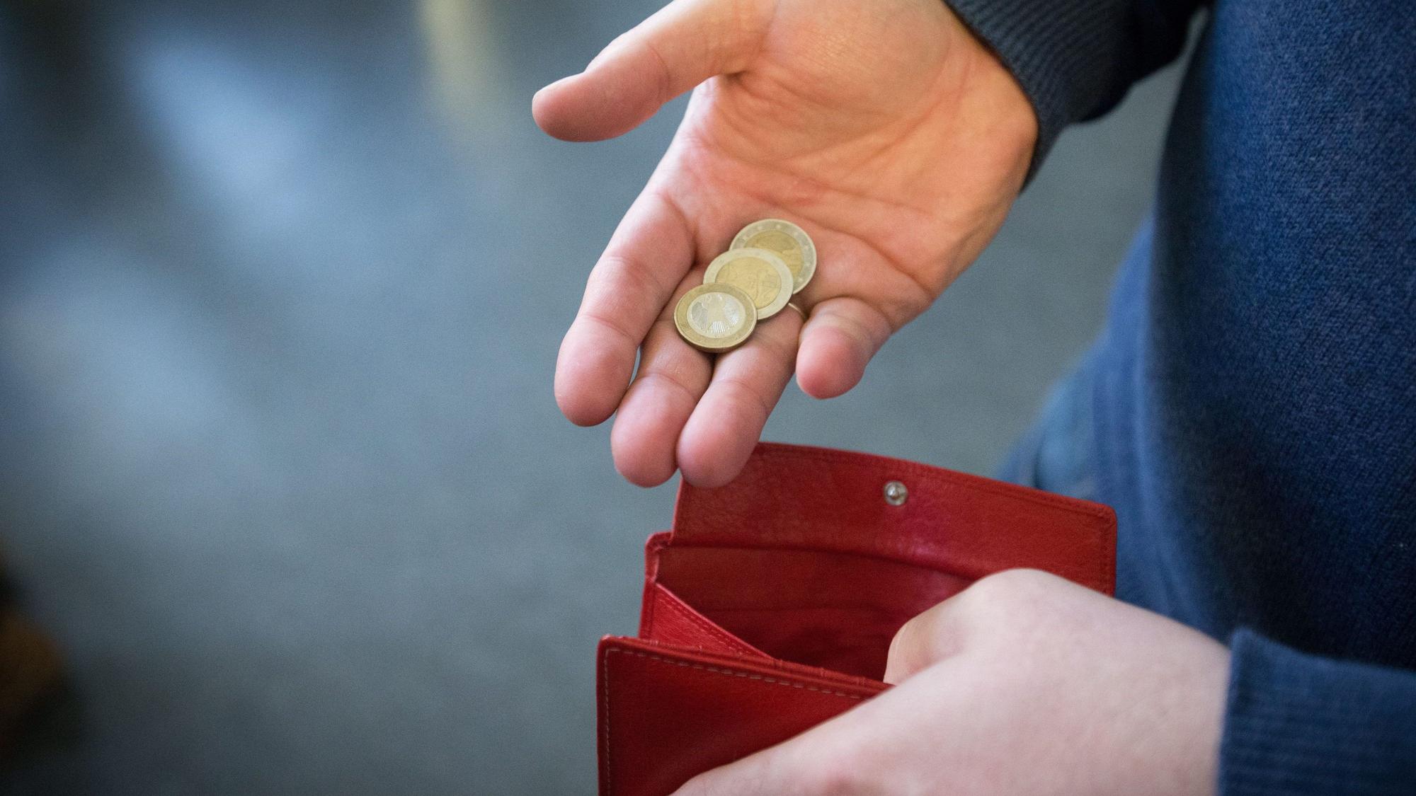 Münzen im Wert von fünf Euro werden auf diese undatierten Symbolbild über ein rotes Portemonnaie gehalten.