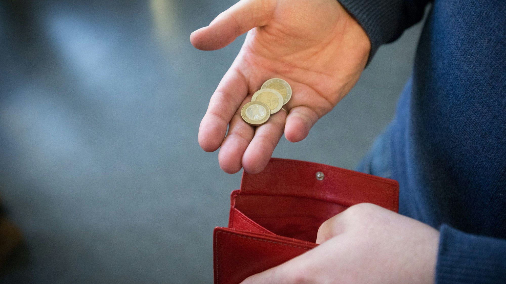 Münzen im Wert von fünf Euro werden auf diese undatierten Symbolbild über ein rotes Portemonnaie gehalten.