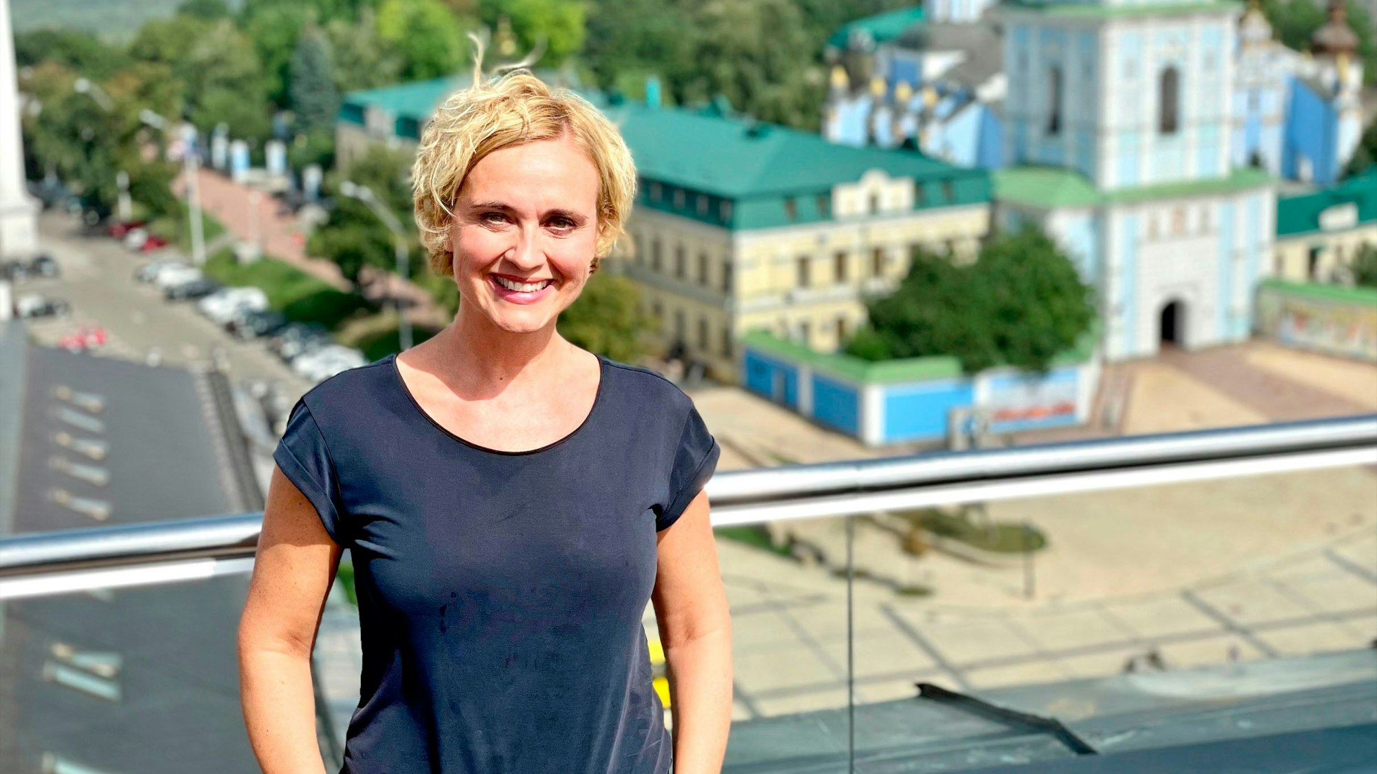 Caren Miosga, Moderatorin der ARD-"Tagesthemen" steht auf einem Balkon - im Hintergrund ist das St. Michaelskloster zu sehen. Anlässlich des inzwischen sechs Monate dauernden Angriffskrieges gegen die Ukraine kommen die ARD-«Tagesthemen» am 24.08.2022 ab 22.15 Uhr live aus Kiew. +++ dpa-Bildfunk +++