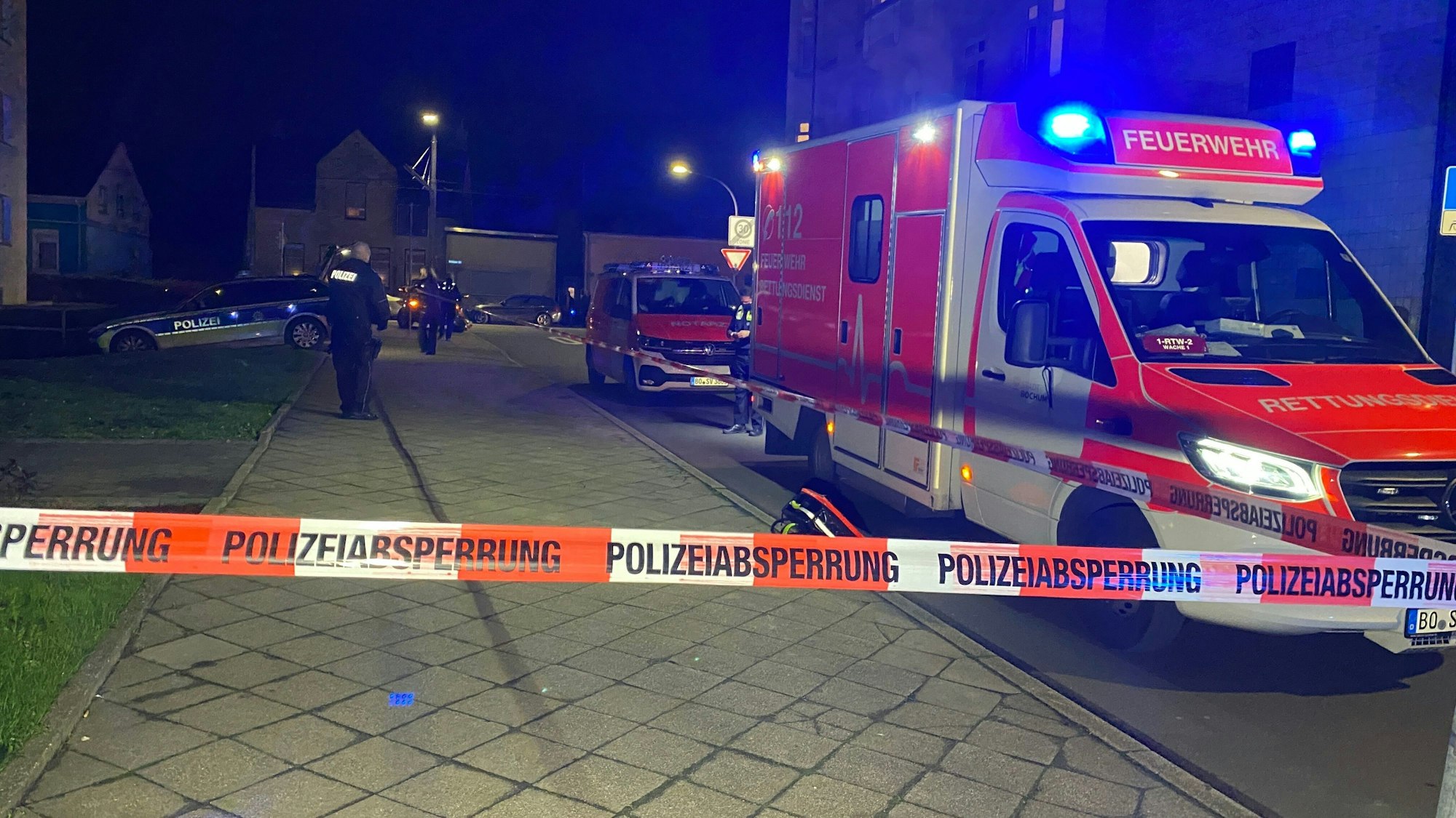 Polizei und Rettungswagen stehen an einem Gehsteig.