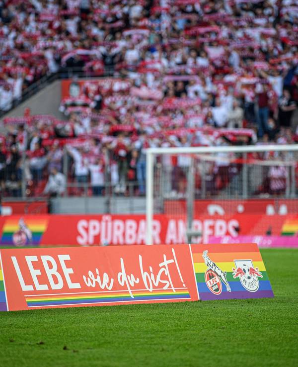 Ein Aufsteller „Lebe wie du bist!“ steht auf dem Rasen des Rhein-Energie-Stadions in Köln.