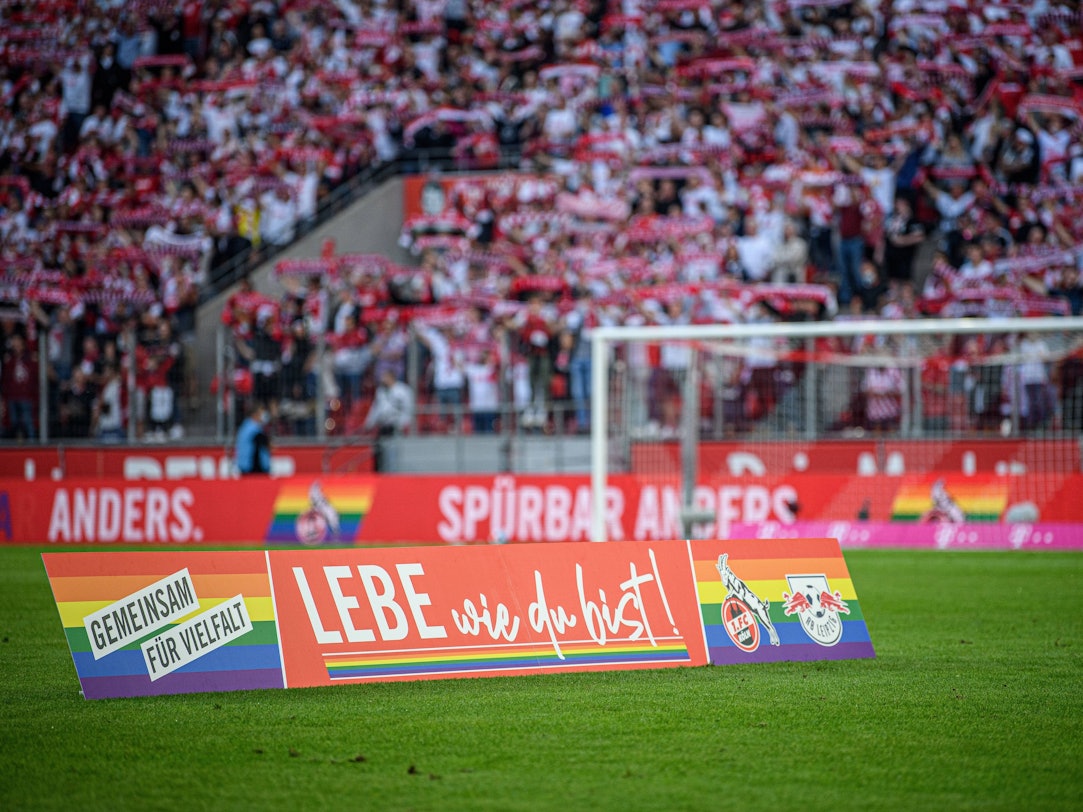 Ein Aufsteller „Lebe wie du bist!“ steht auf dem Rasen des Rhein-Energie-Stadions in Köln.