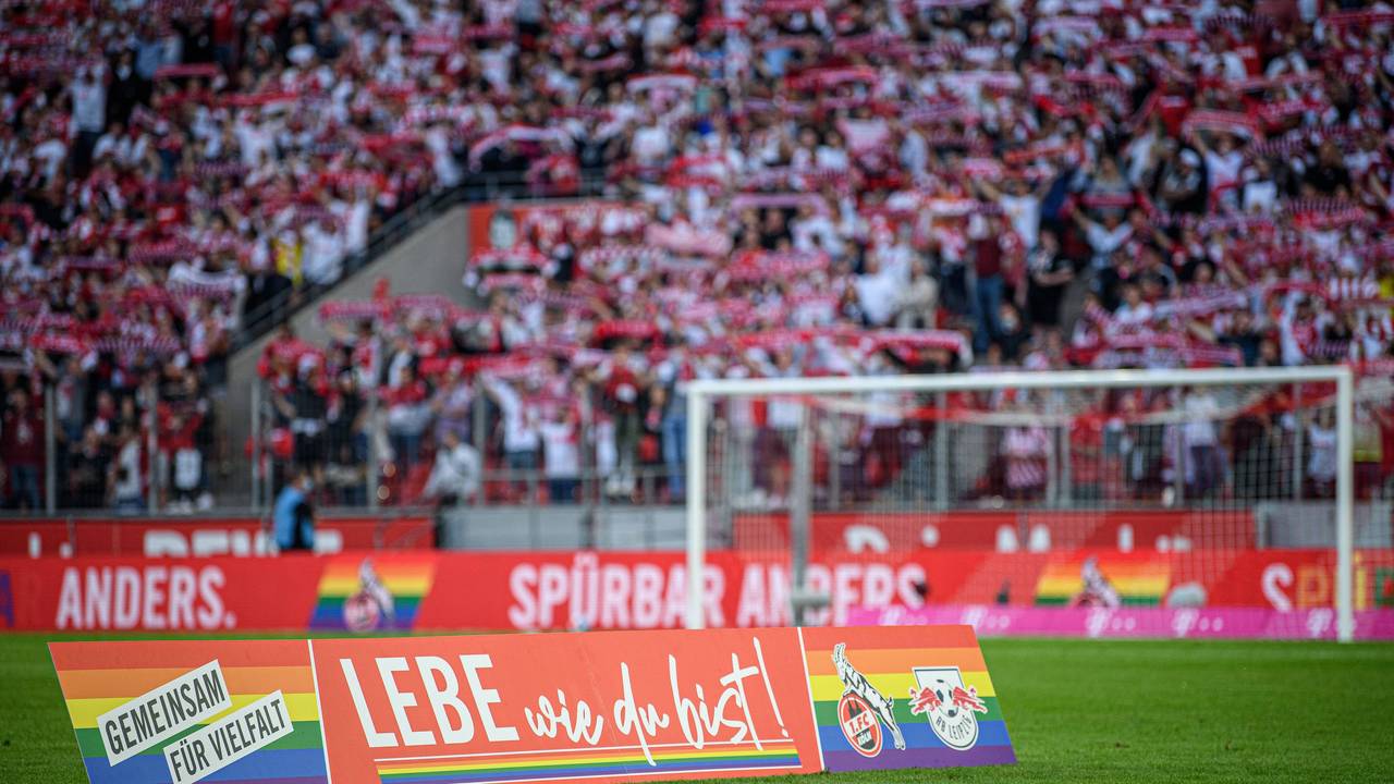 Ein Aufsteller „Lebe wie du bist!“ steht auf dem Rasen des Rhein-Energie-Stadions in Köln.