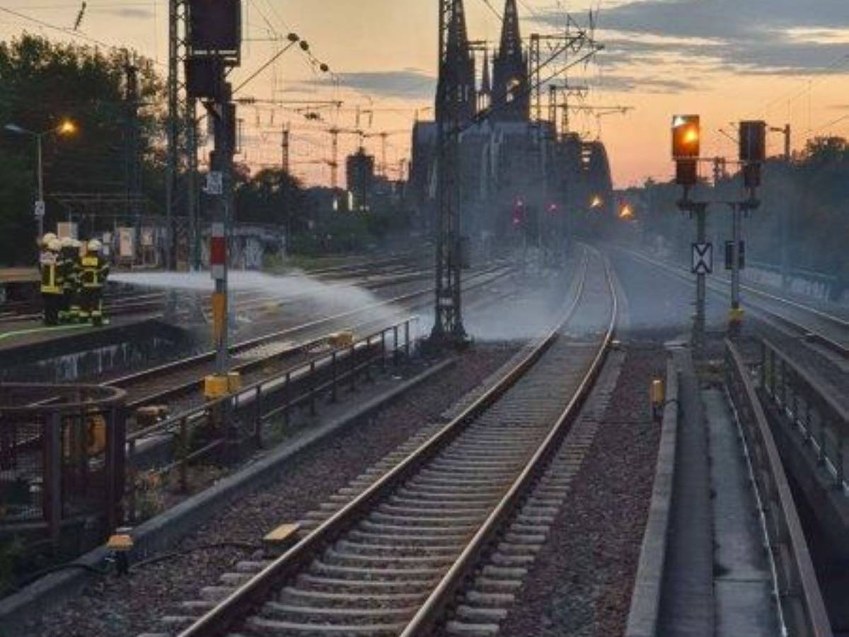 Feuerwehrleute löschen einen Brand zwischen zwei Bahngleisen.