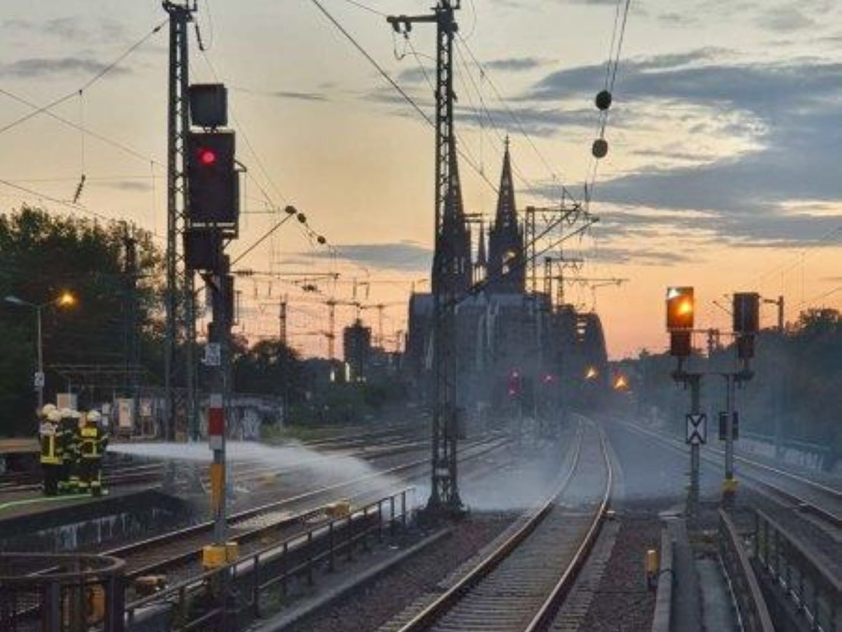 Feuerwehrleute löschen einen Brand zwischen zwei Bahngleisen.