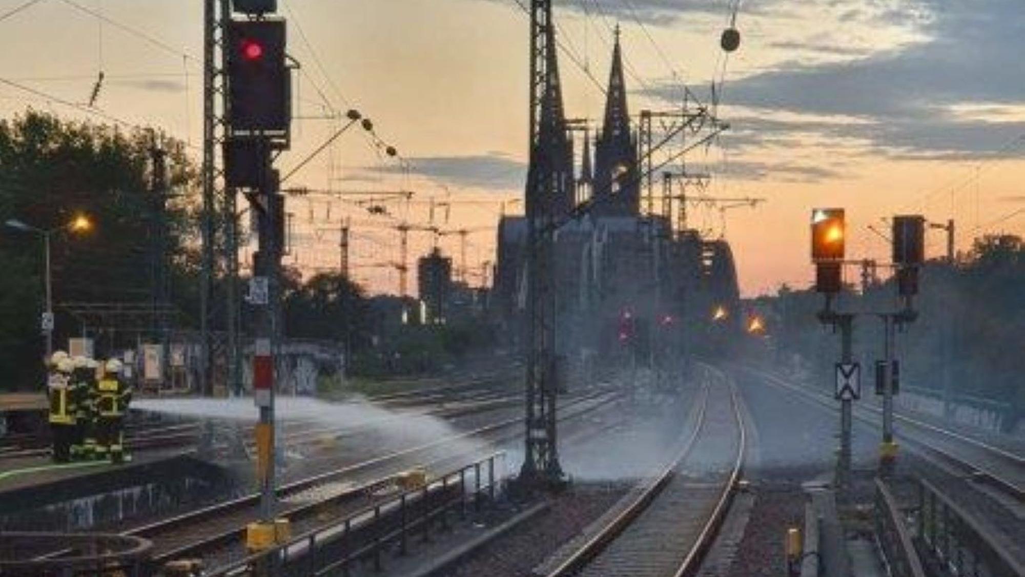 Feuerwehrleute löschen einen Brand zwischen zwei Bahngleisen.