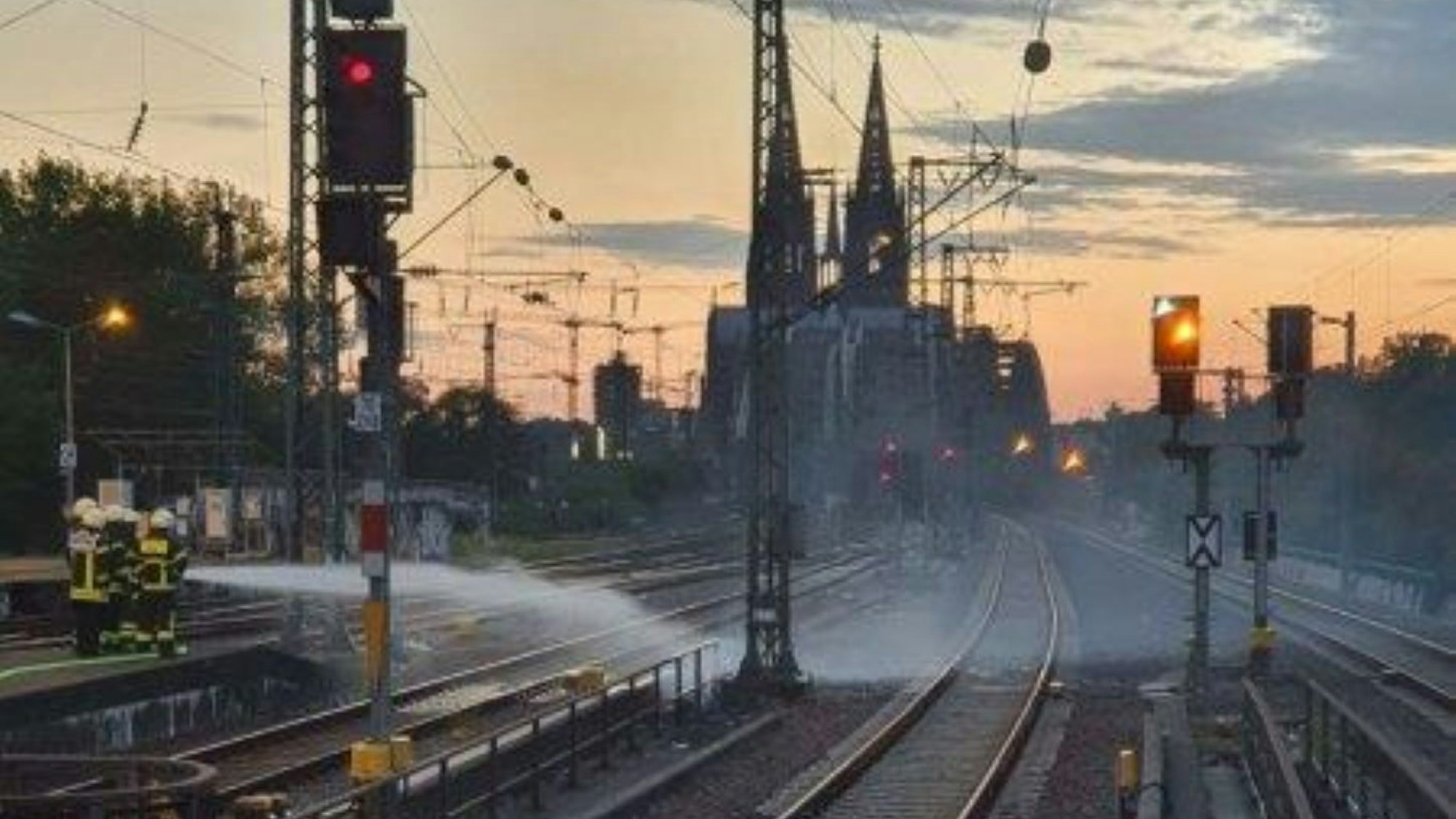 Feuerwehrleute löschen einen Brand zwischen zwei Bahngleisen.