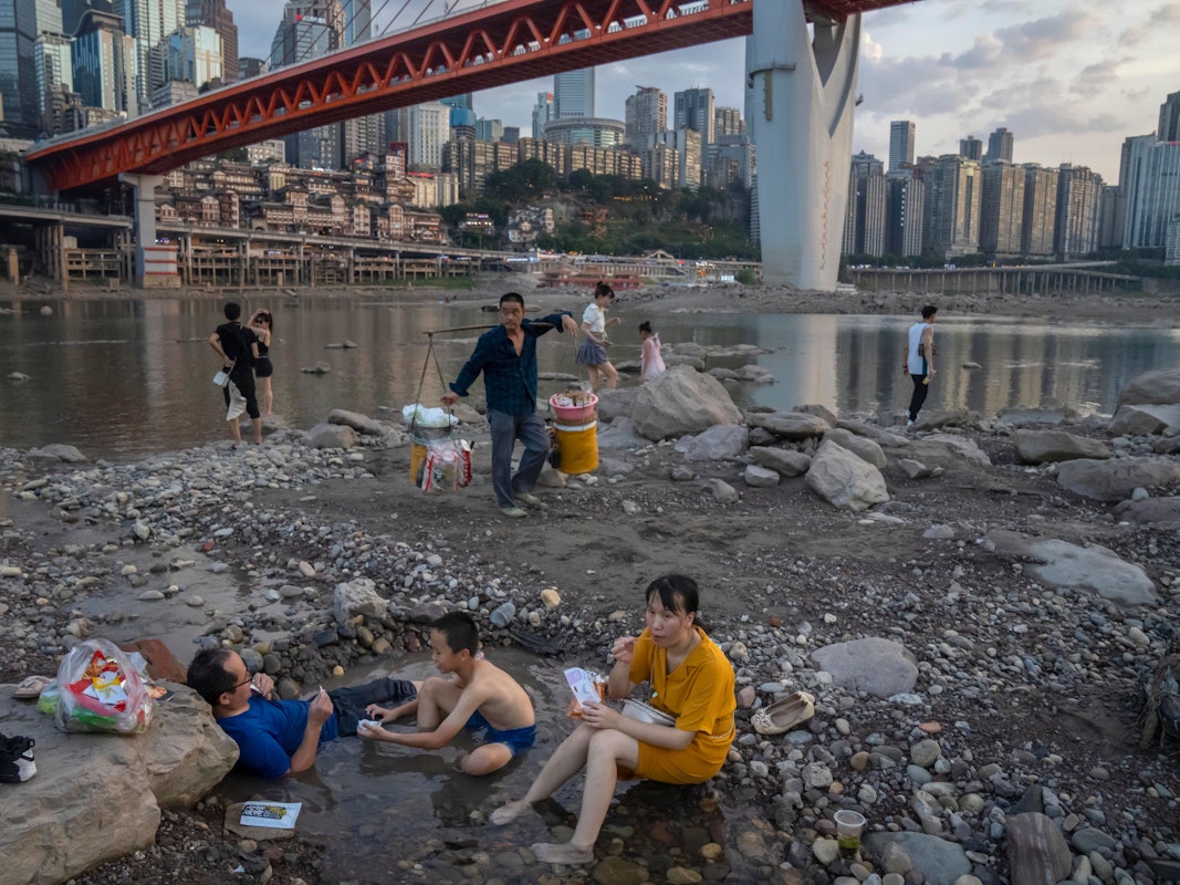 Chongqing: Menschen sitzen in einem flachen Wasserbecken im Flussbett des Jialing-Flusses, eines Nebenflusses des Jangtse, in der südwestchinesischen Stadt Chongqing.