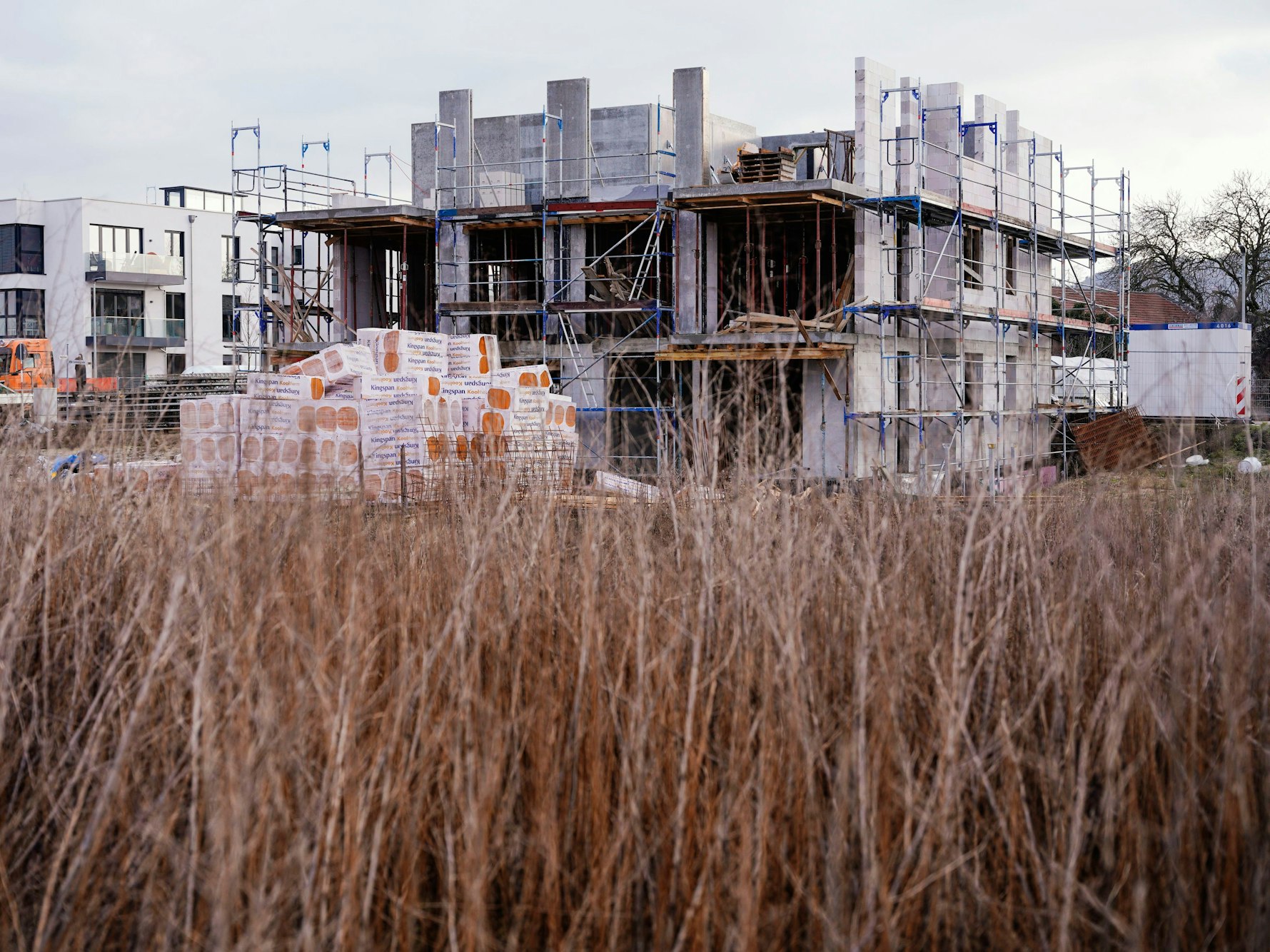 Baustelle mit halb fertigem Haus in einem Wohngebiet.