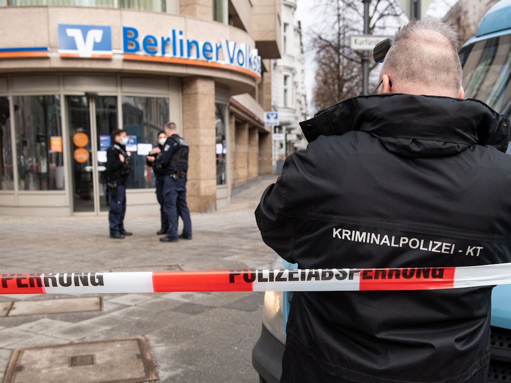 Polizeibeamte in Berlin sichern vor einer Bank an einem Geldtransporter Spuren, nachdem dieser überfallen wurde.