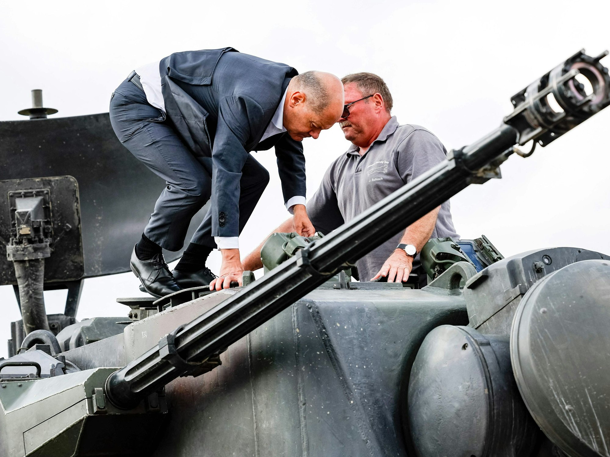 Bundeskanzler Olaf Scholz (l.) klettert mit dem Ausbildungsleiter des Waffenherstellers Krauss-Maffei Jürgen Schoch auf einen deutschen Flakpanzer Gepard