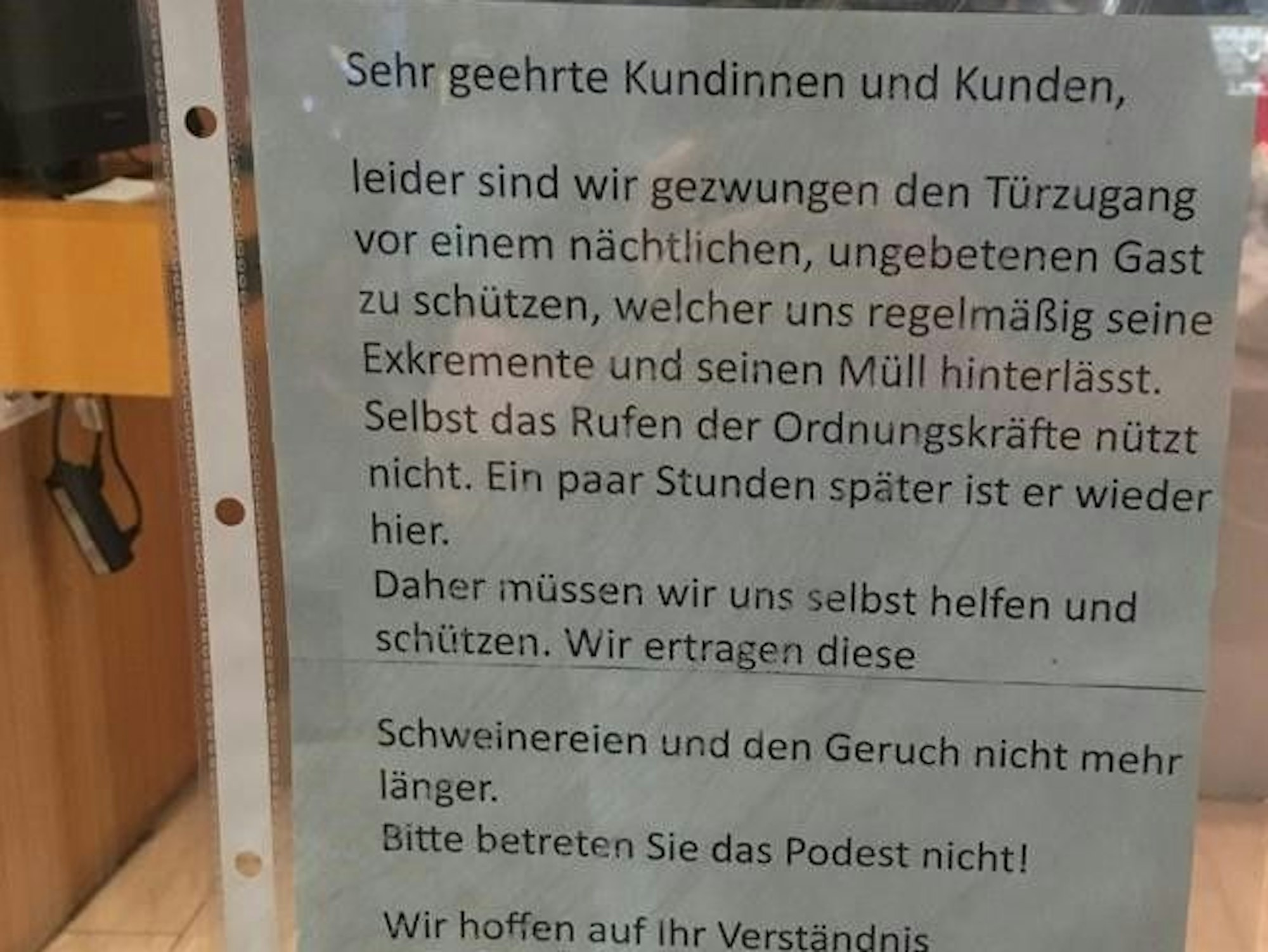Ein Aushang an einem Schuhgeschäft in Köln mit dem Hinweis auf ein Nagelbrett im Eingangsbereich.