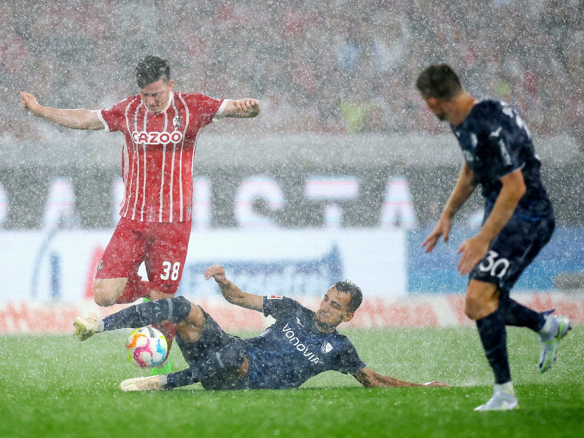 Freiburgs Michael Gregoritsch wird von Bochums Erhan Masovic im Starkregen getackelt