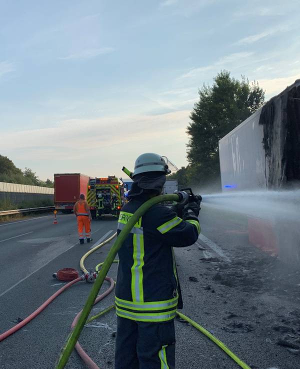 Ein Feuerwehrmann löscht nach dem Brand eines Lkw-Aufliegers noch einige Glutnester ab.