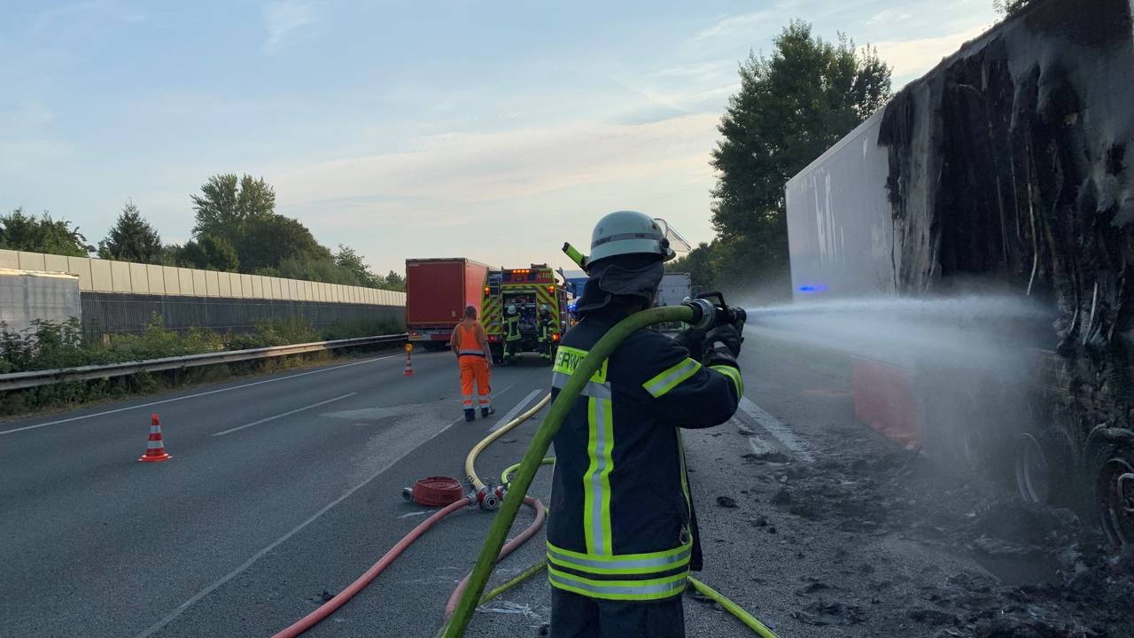 Ein Feuerwehrmann löscht nach dem Brand eines Lkw-Aufliegers noch einige Glutnester ab.