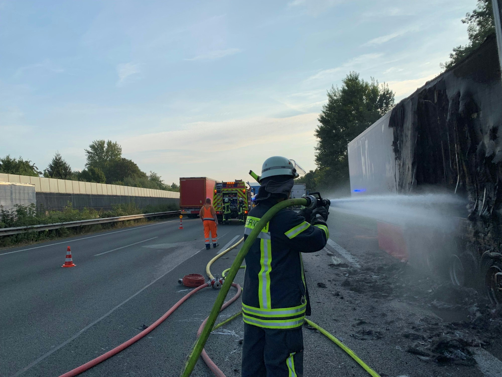 Ein Feuerwehrmann löscht nach dem Brand eines Lkw-Aufliegers noch einige Glutnester ab.