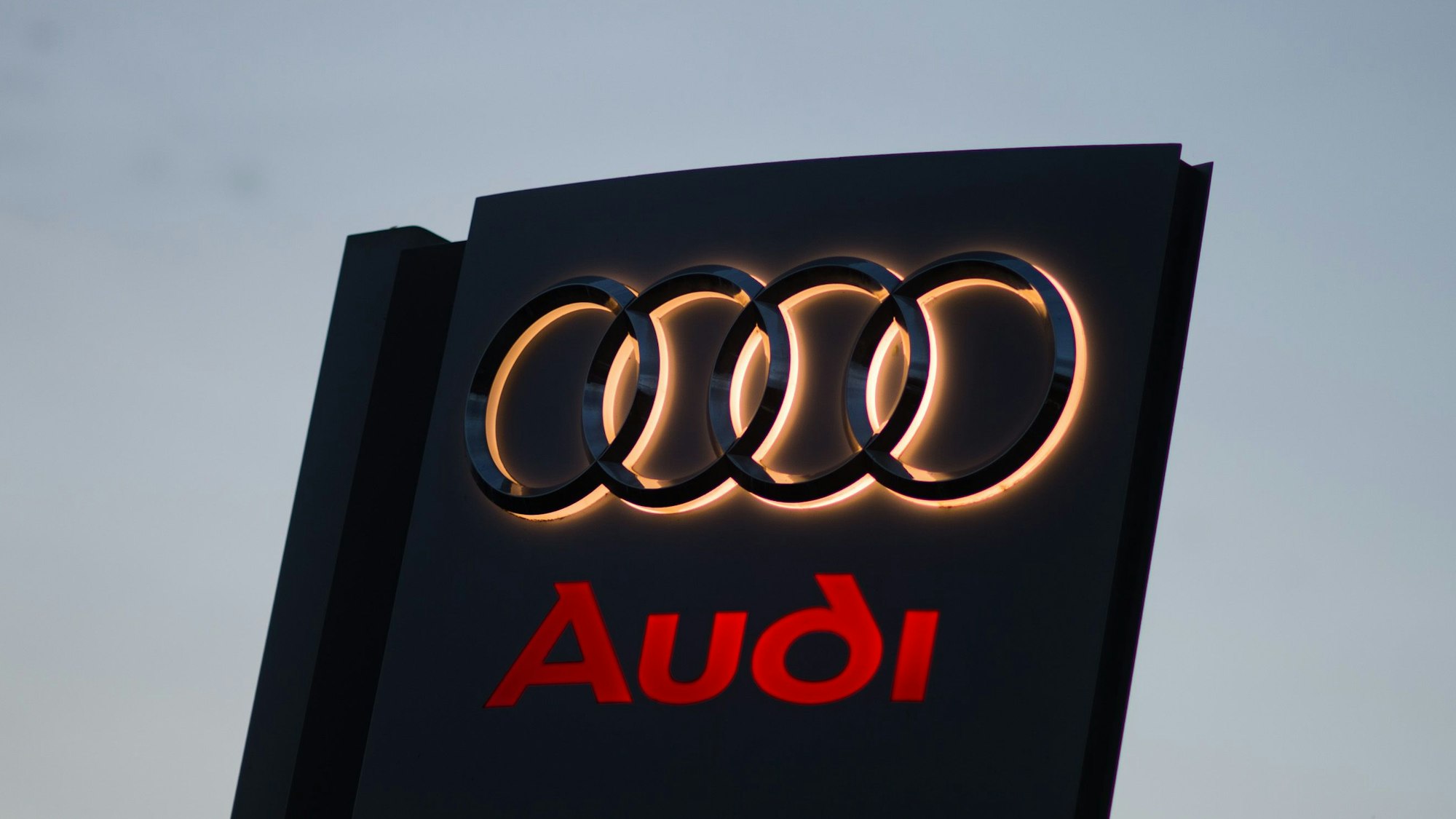 Ein Audi-Logo leuchtet in der Morgendämmerung an einem Volkswagen Autohaus in Hannover (Niedersachsen).