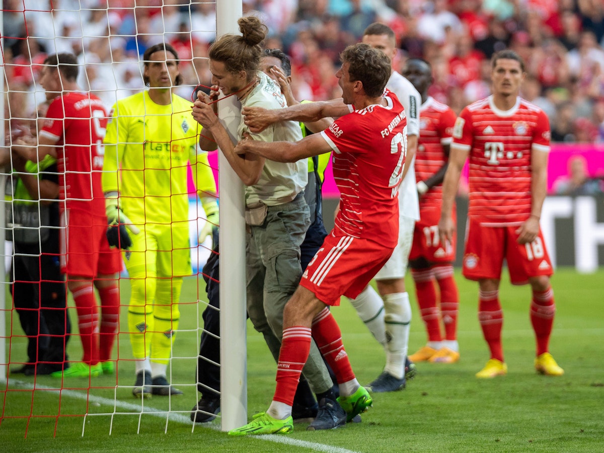 Thomas Müller hindert einen Klima-Aktivisten beim Spiel des FC Bayern gegen Borussia Mönchengladbach daran, sich an einen Torpfosten zu binden.