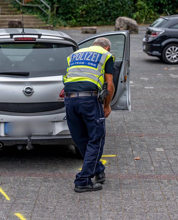 Ein Mitarbeiter der Polizei markiert die Unfallstelle auf einem Parkplatz, wo ein Zweijähriger von einem Auto angefahren und schwer verletzt worden war.