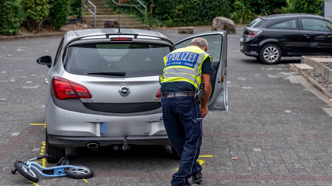 Ein Mitarbeiter der Polizei markiert die Unfallstelle auf einem Parkplatz, wo ein Zweijähriger von einem Auto angefahren und schwer verletzt worden war.
