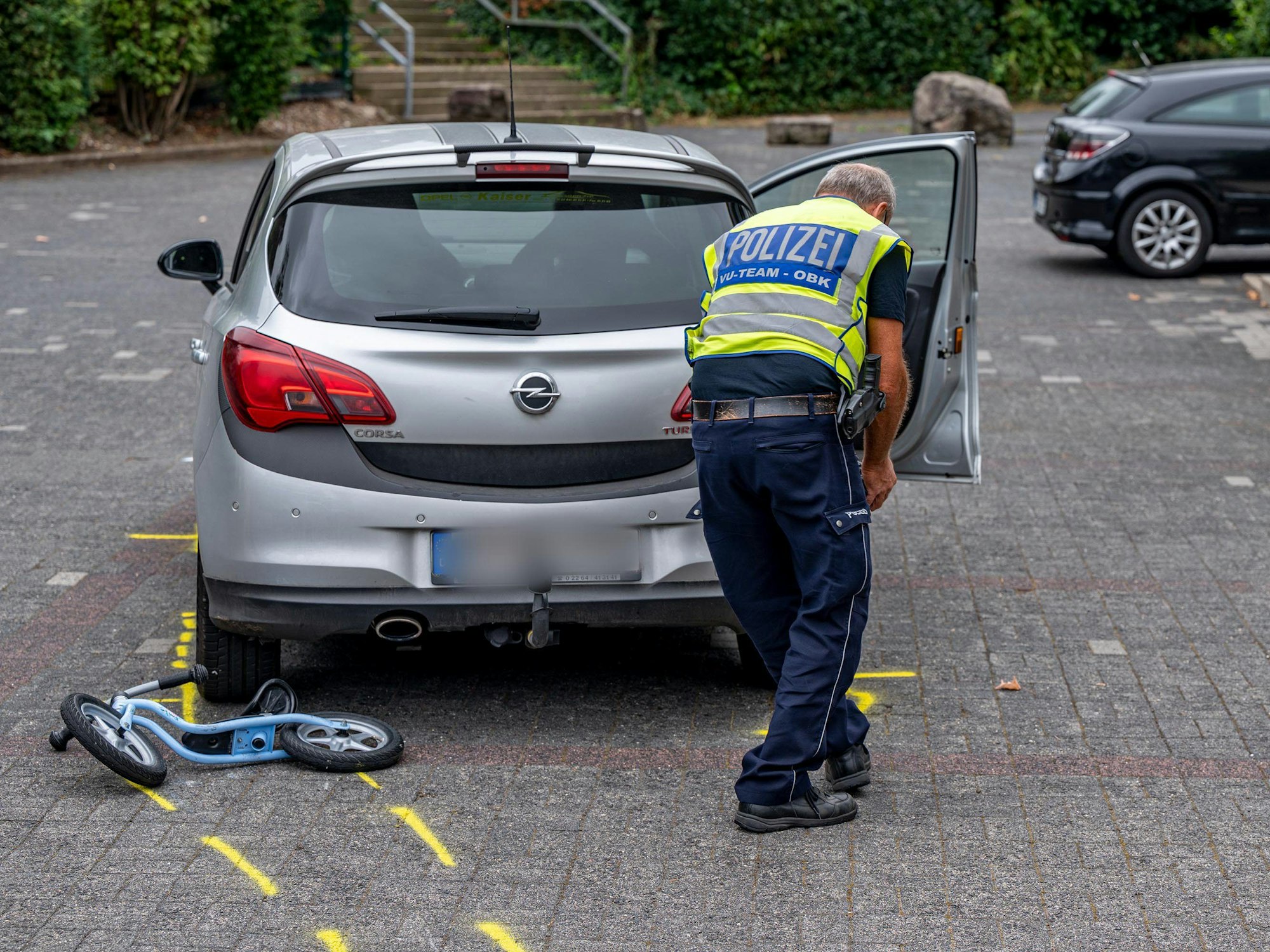 Ein Mitarbeiter der Polizei markiert die Unfallstelle auf einem Parkplatz, wo ein Zweijähriger von einem Auto angefahren und schwer verletzt worden war.